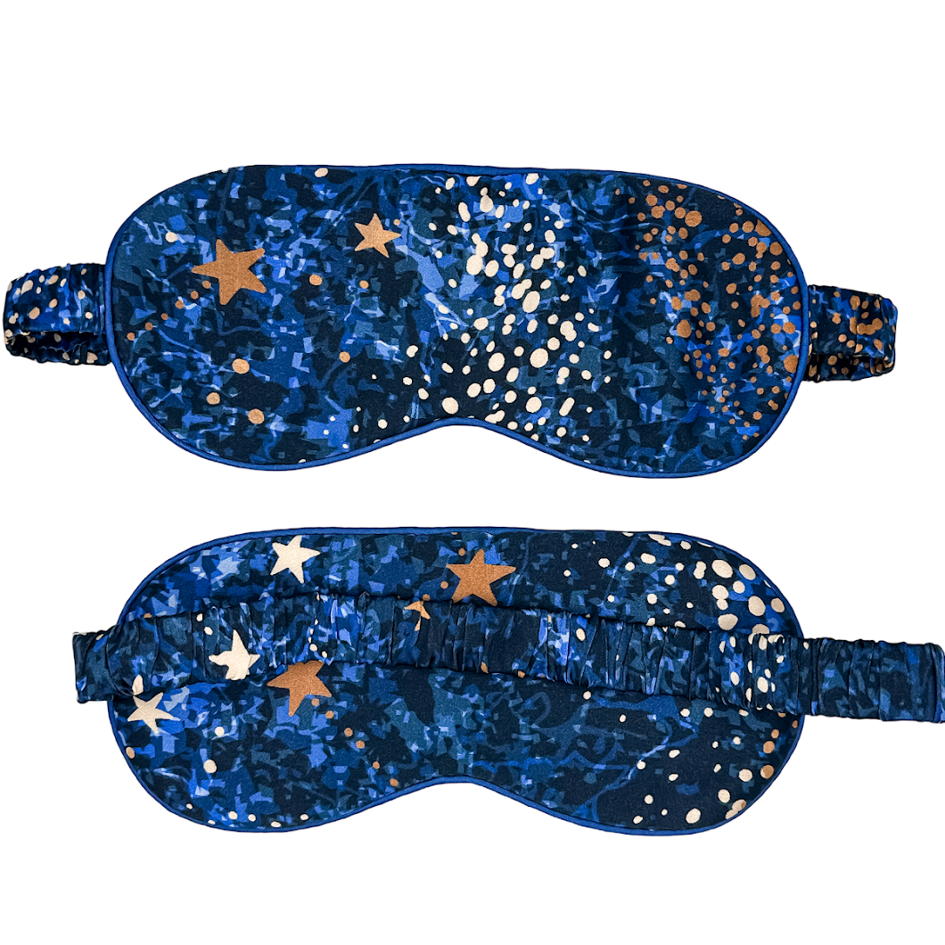 Antifaz para dormir de seda Cielo Nocturno en azul con estampado de estrellas doradas, vista frontal y trasera.