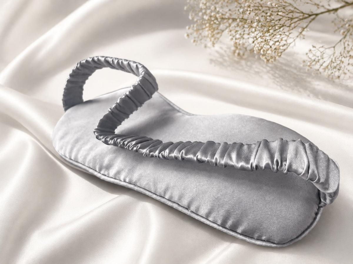 Antifaz para dormir de seda morera color gris sobre tejido satinado con flores blancas