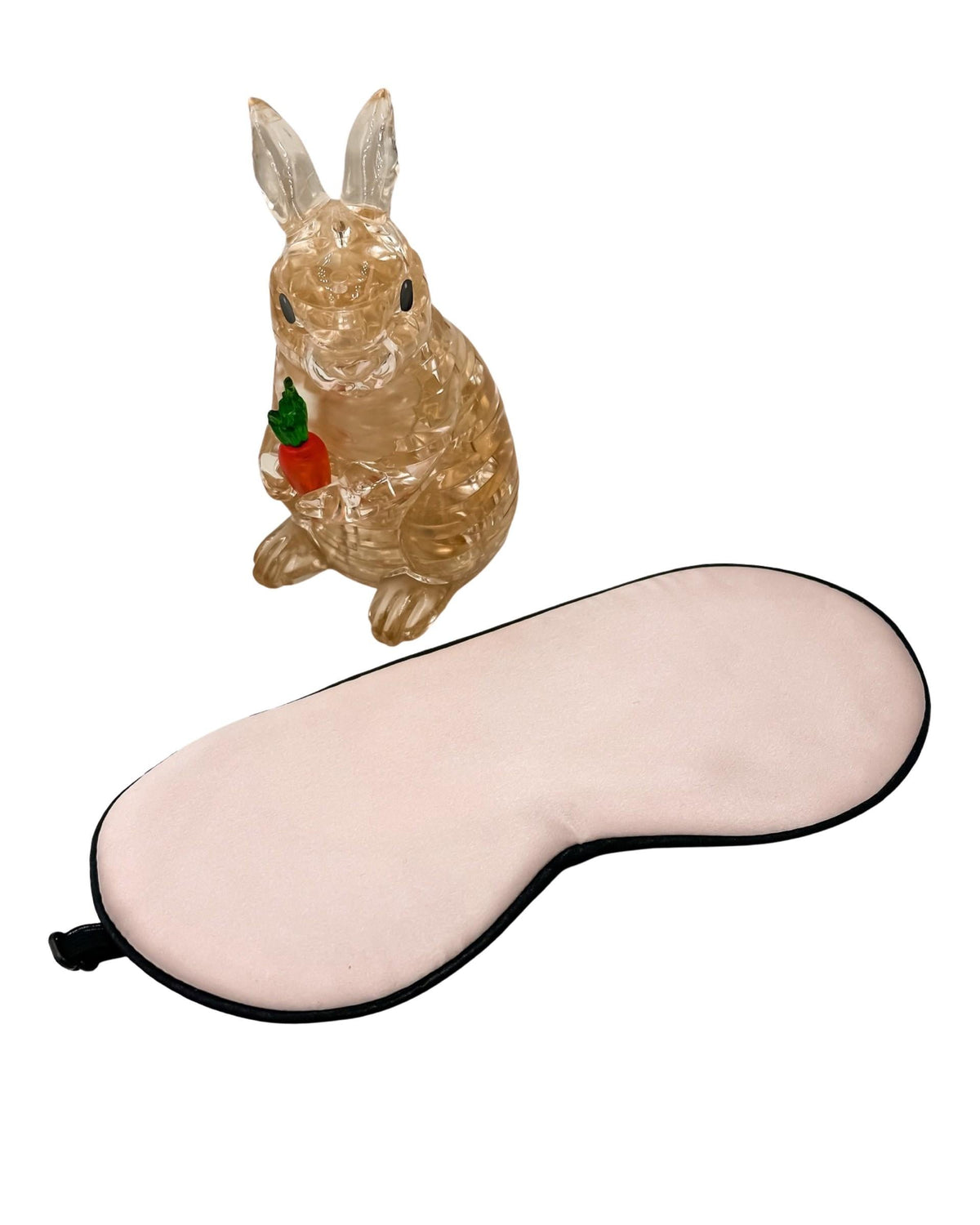 ntifaz de seda rosa para niños con ribete negro junto a una figura de conejo