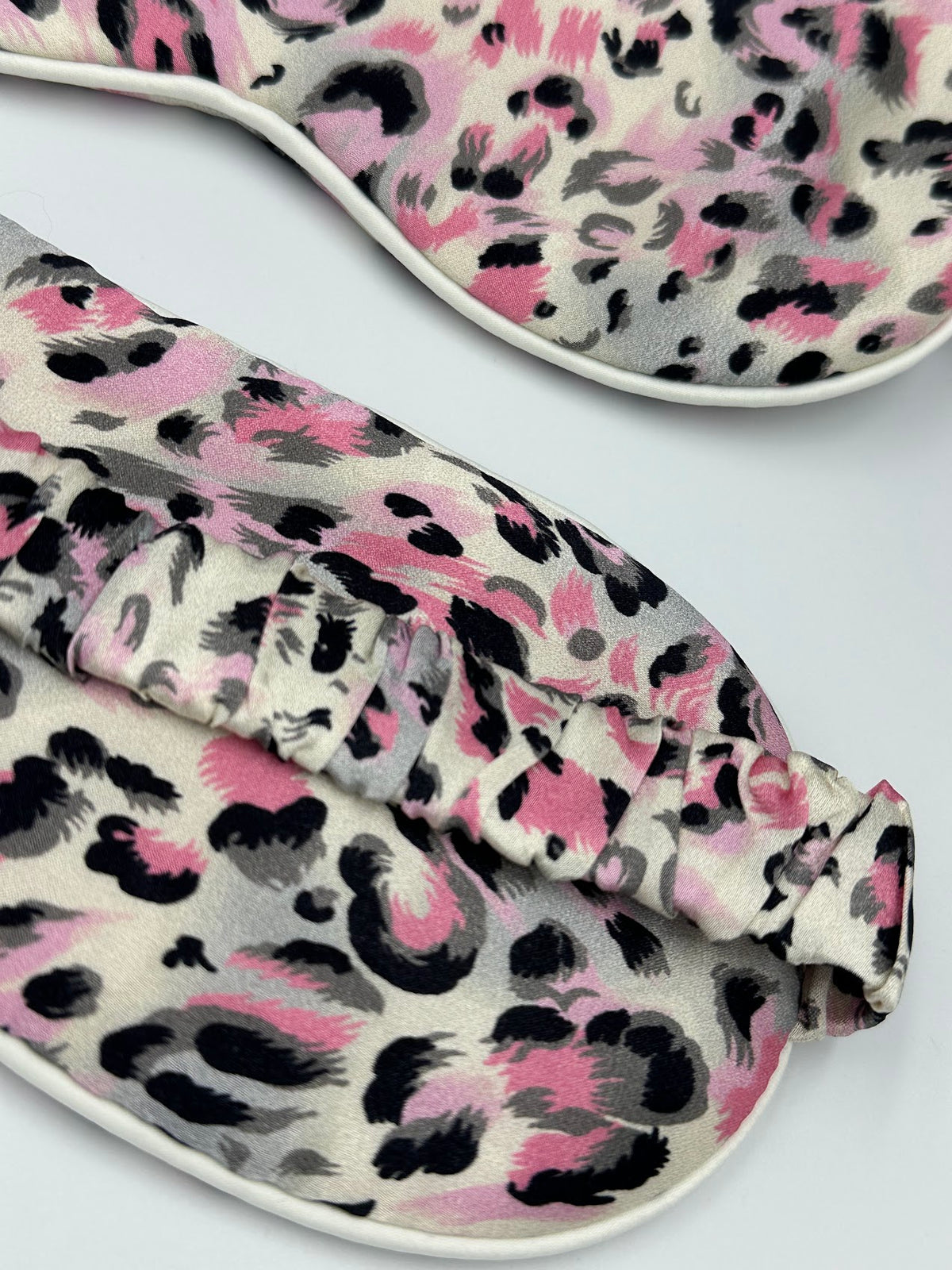 Detalle frontal y trasero del antifaz para dormir de seda morera Rosa Salvaje con estampado animal rosa, gris y negro