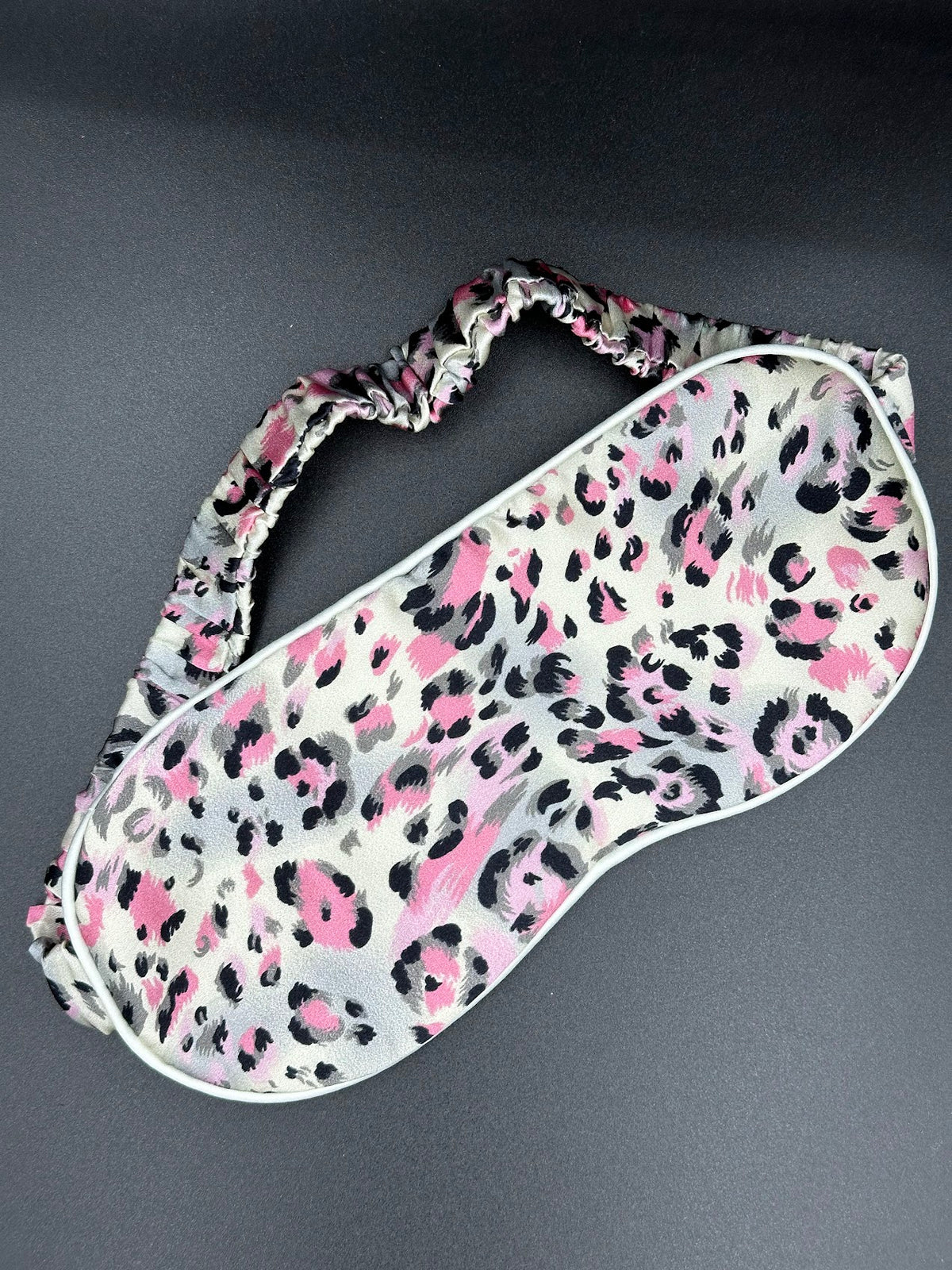 Antifaz para dormir de seda morera Rosa Salvaje con estampado animal rosa, gris y negro sobre fondo oscuro