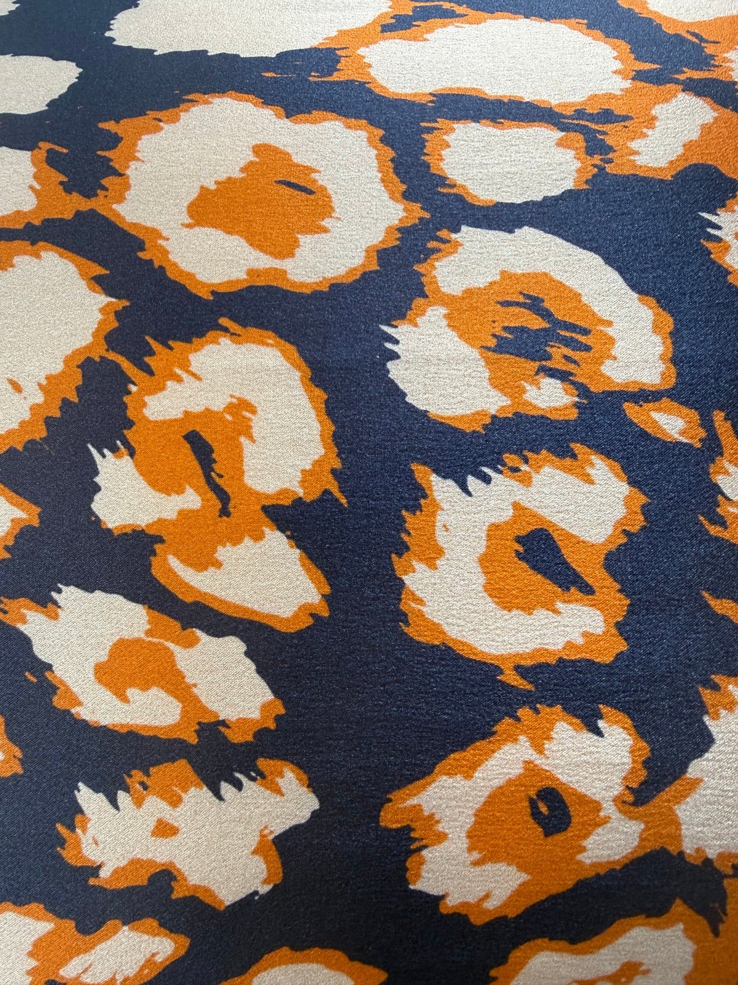 Detalle del estampado fanimal en azul marino, beige y naranja de una funda de almohada de seda