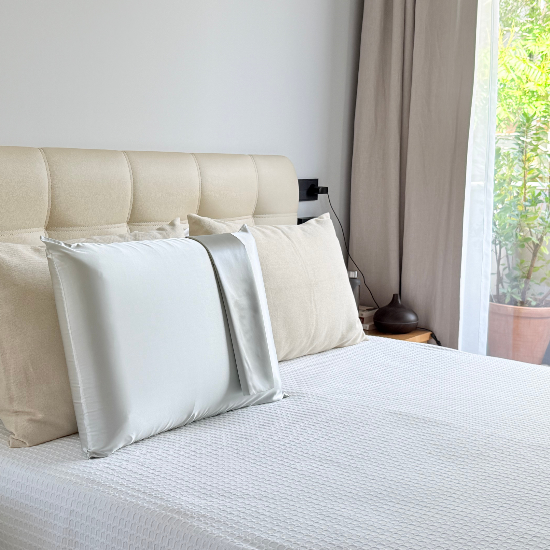 Funda de almohada de seda de morera color azul claro colocada sobre una cama