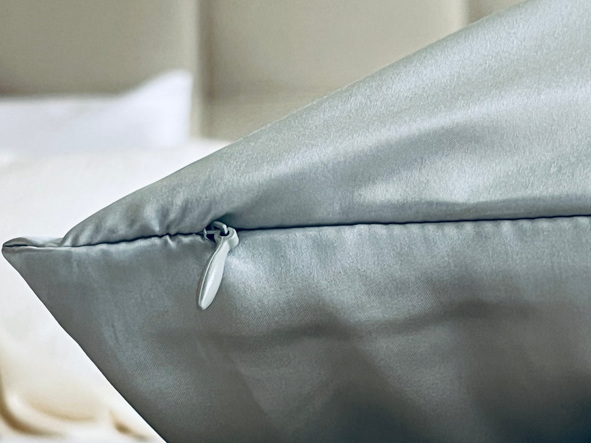 Detalle de la cremallera de una funda de almohada de seda de morera color azul claro