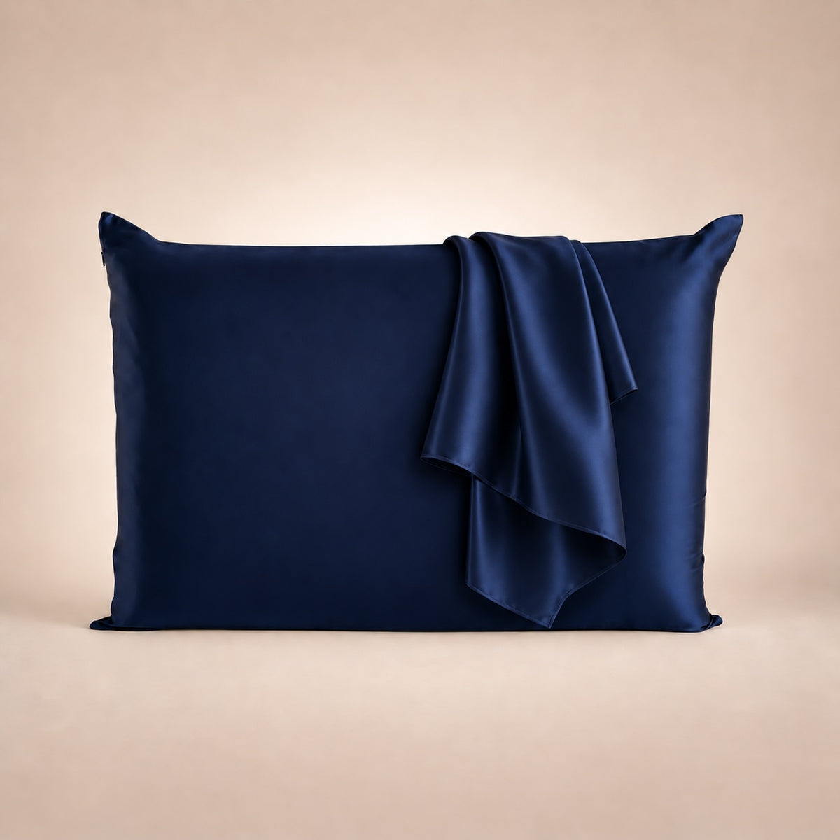 Funda de almohada de seda azul marino con tejido de seda a juego sobre fondo beige
