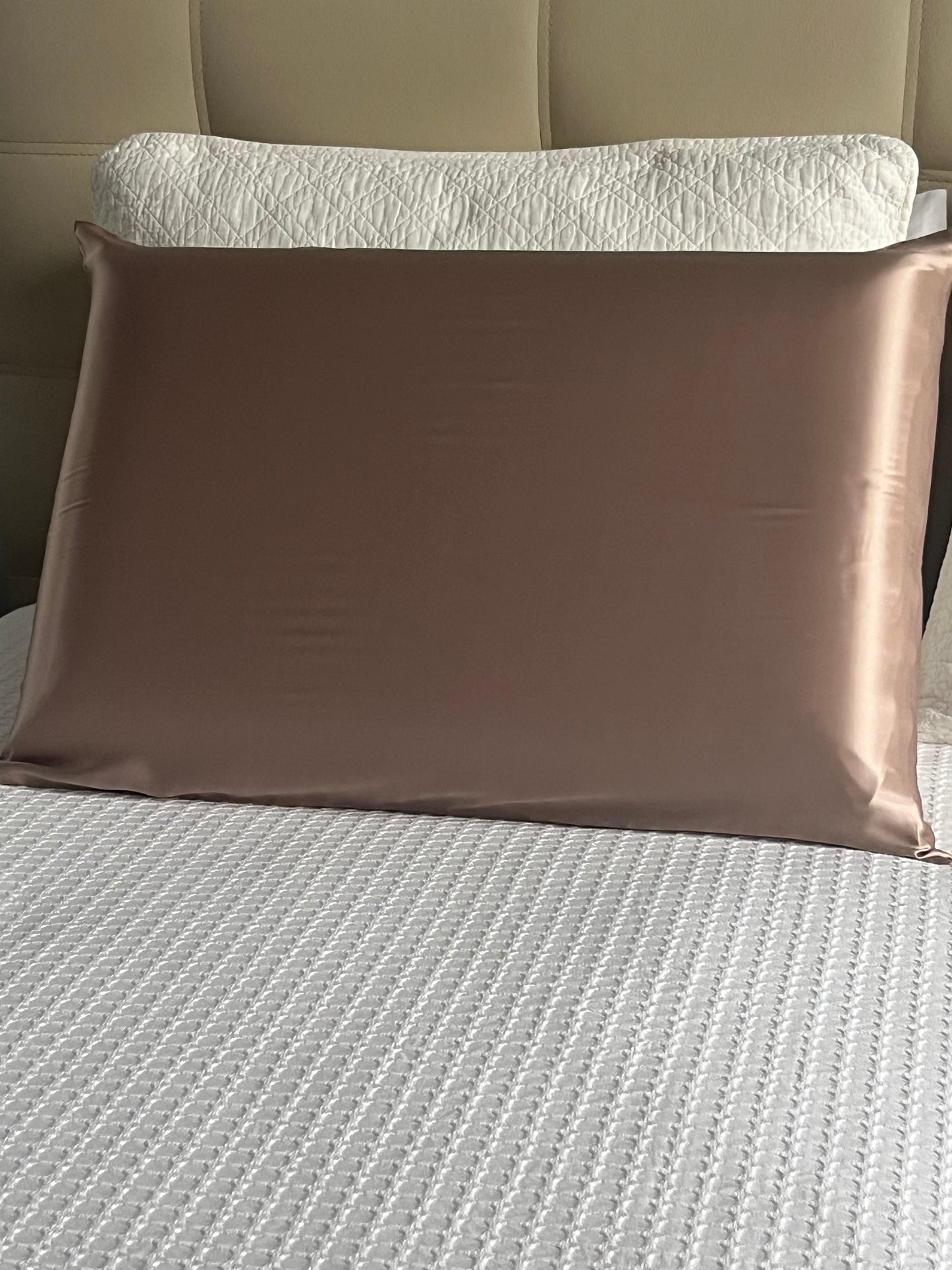 Funda de almohada de seda de morera color bronce colocada sobre una cama