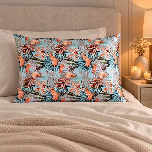 Funda de almohada de seda con estampado tropical azul y coral sobre una cama en un dormitorio elegante iluminado con velas