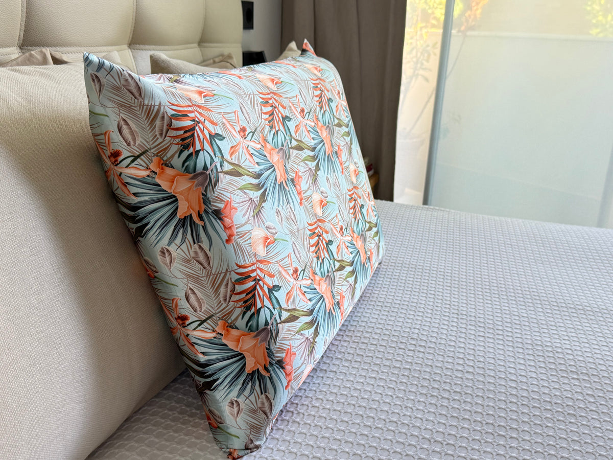 Funda de almohada de seda con estampado tropical sobre una cama