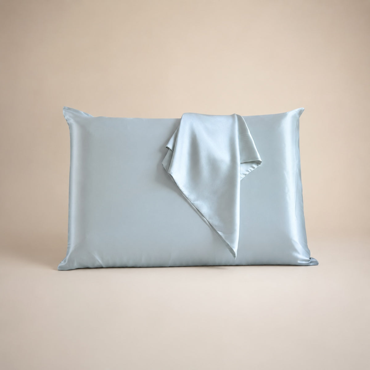 Funda de almohada de seda de morera color azul claro sobre fondo beige
