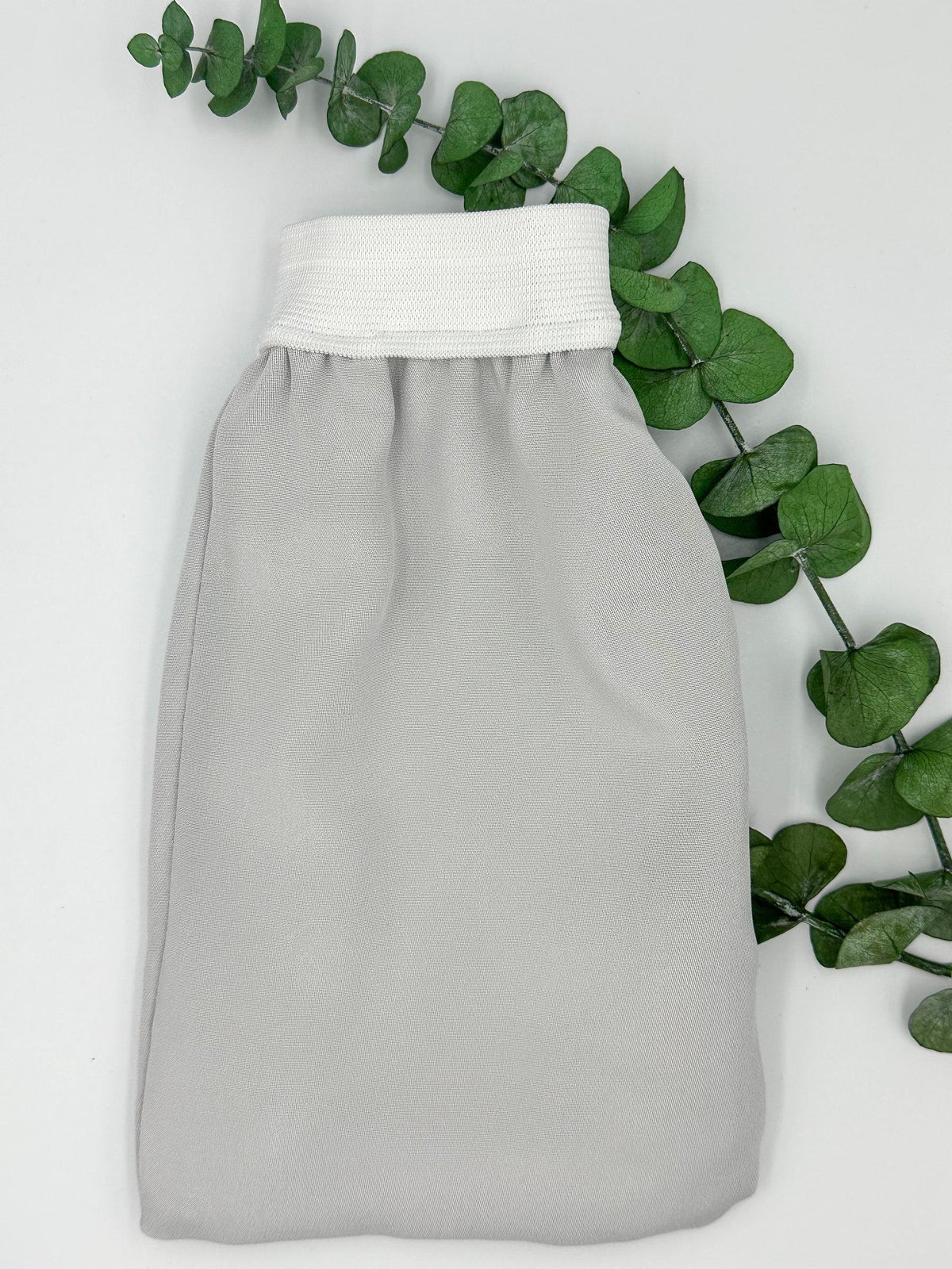 Guante exfoliante de seda gris con puño blanco para el cuidado corporal