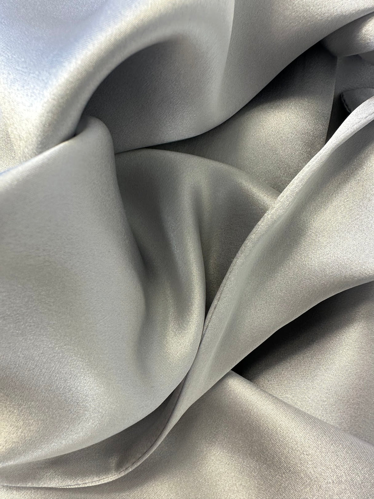 Detalle en primer plano del tejido de seda gris plata y su brillo natural
